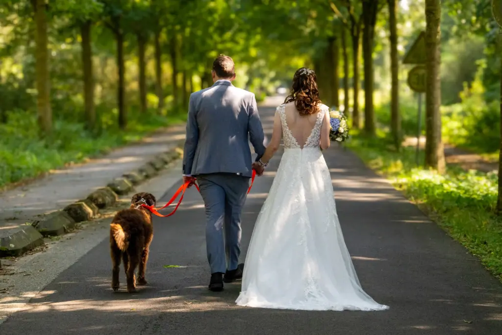 Hochzeitsfoto in Willich – Brautpaar mit Hund auf einer Allee